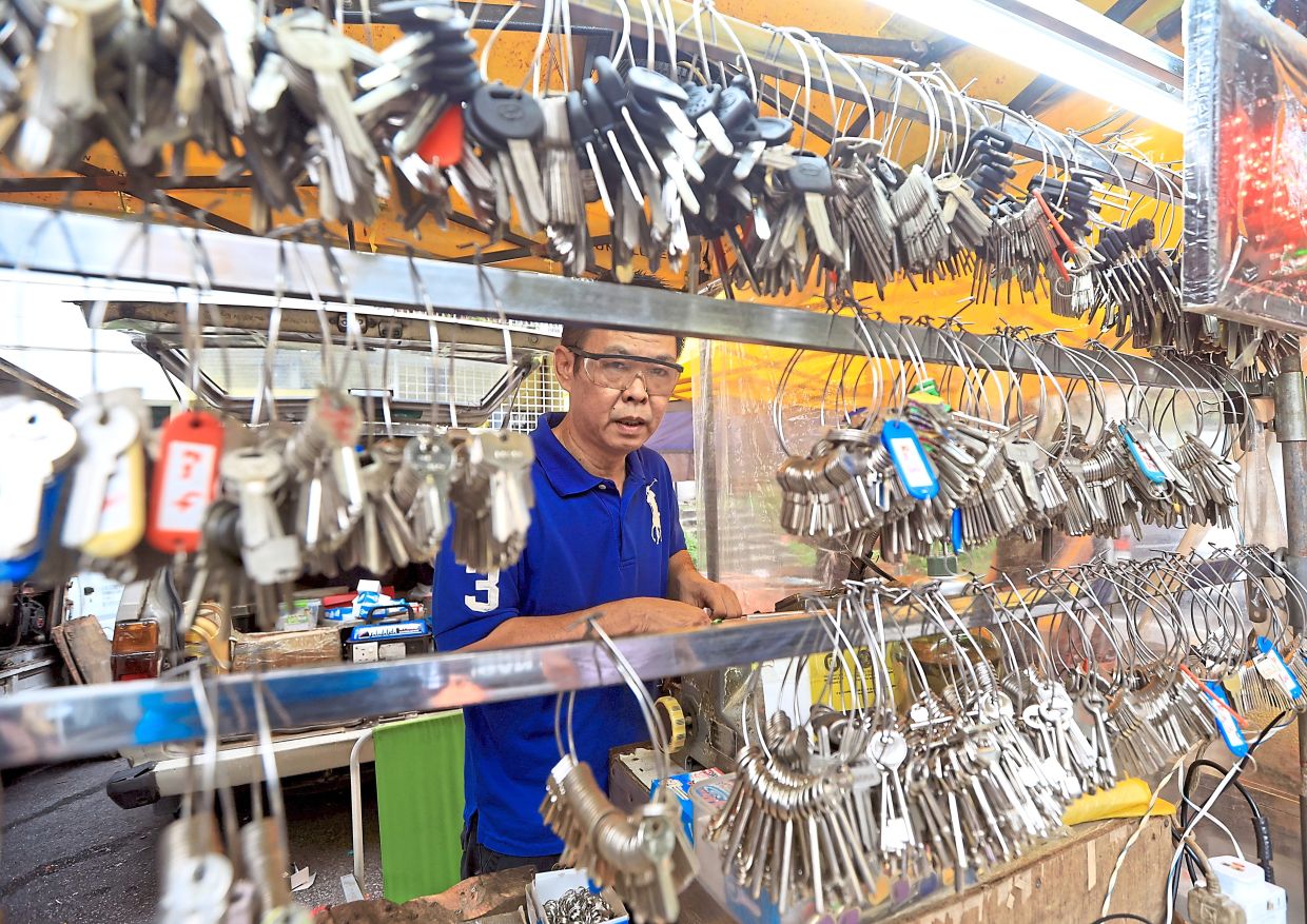 A locksmith offering key duplication services at the pasar malam.