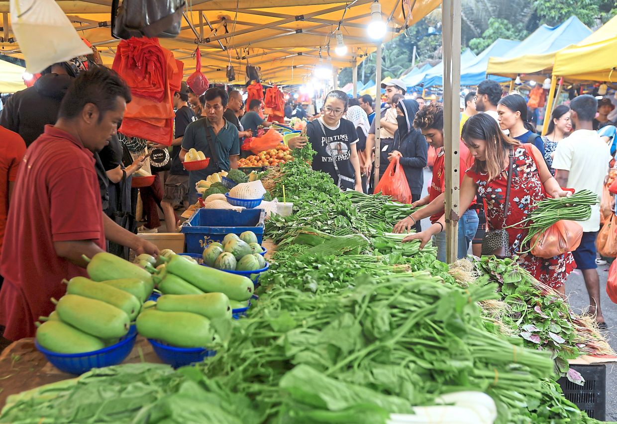 Shoppers browsing a wide selection of greens at a vegetable stall in Section 17 night market. — Photos: CHAN TAK KONG/The Star