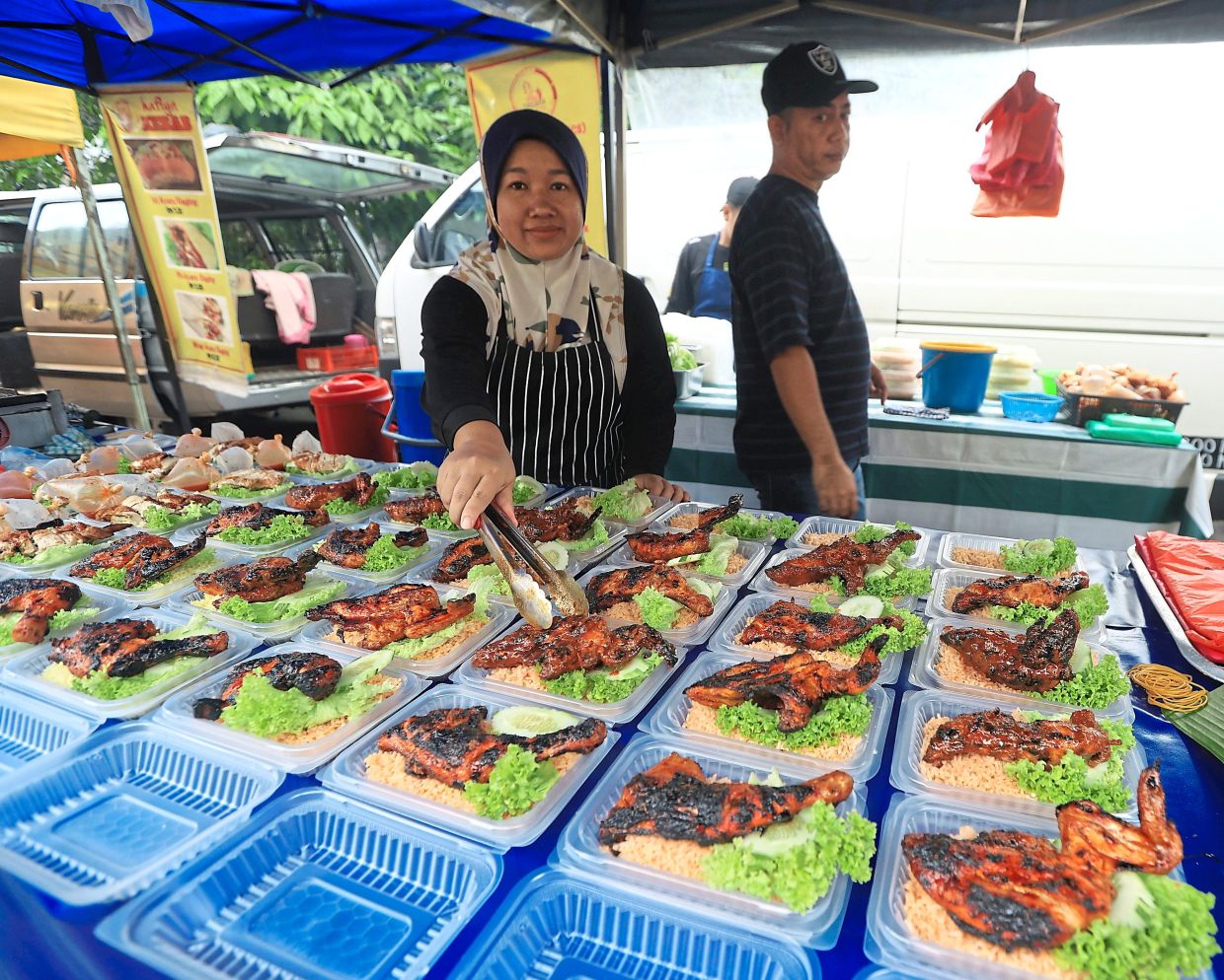 A vendor serving packs of grilled chicken rice, ready for takeaway.