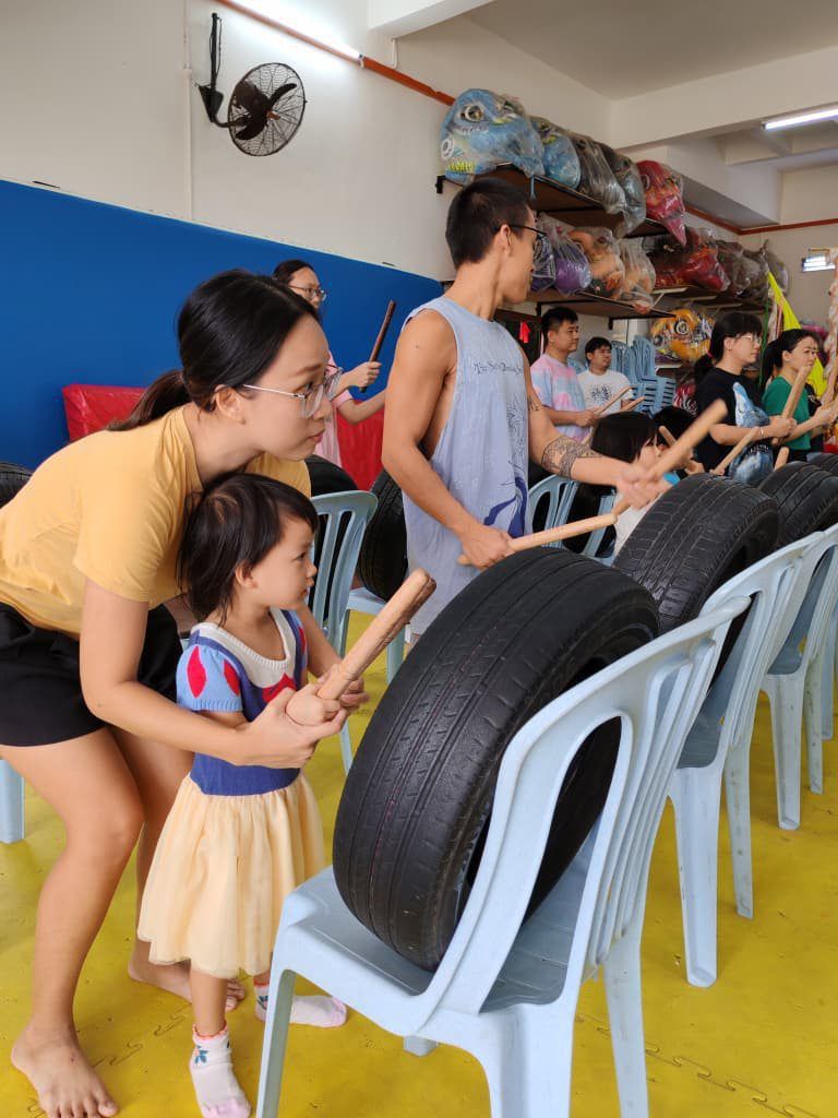 A mother and her young daughter striking on a tyre for practice during a drums training session in Ipoh.
