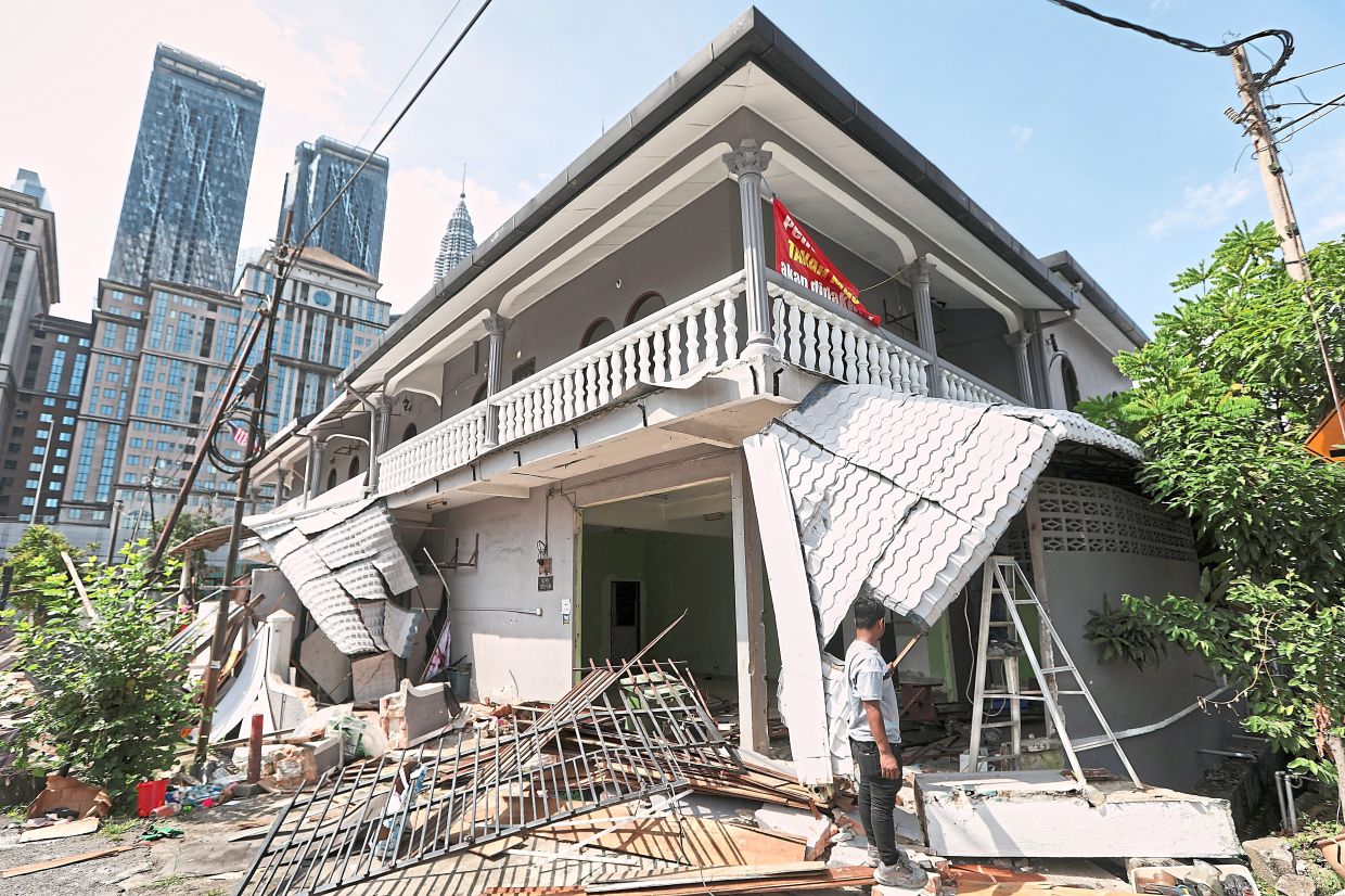 A scrap metal contractor surveying what can be salvaged from a partially demolished house. — Photos: YAP CHEE HONG/The Star 