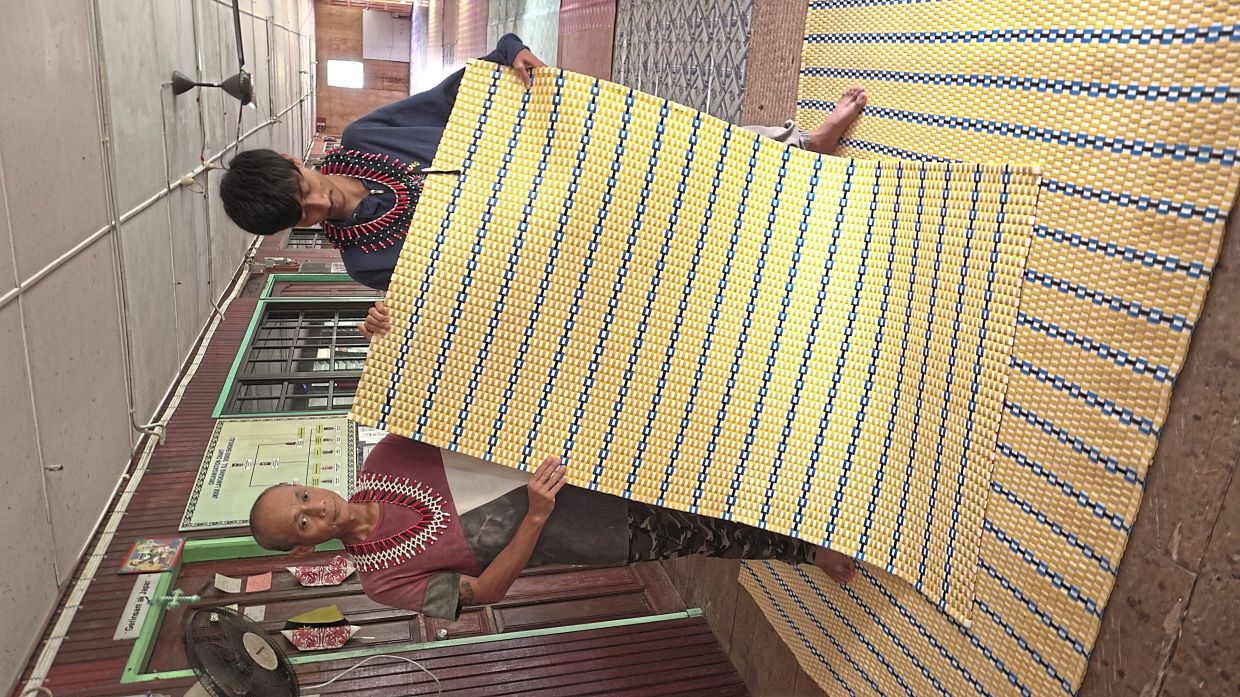 Felixous and his father Taka Utoi showing the mats they wove in three days during the training programme.