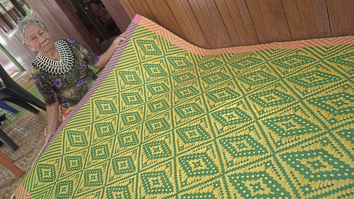 Berenai proudly showing the mat she made.