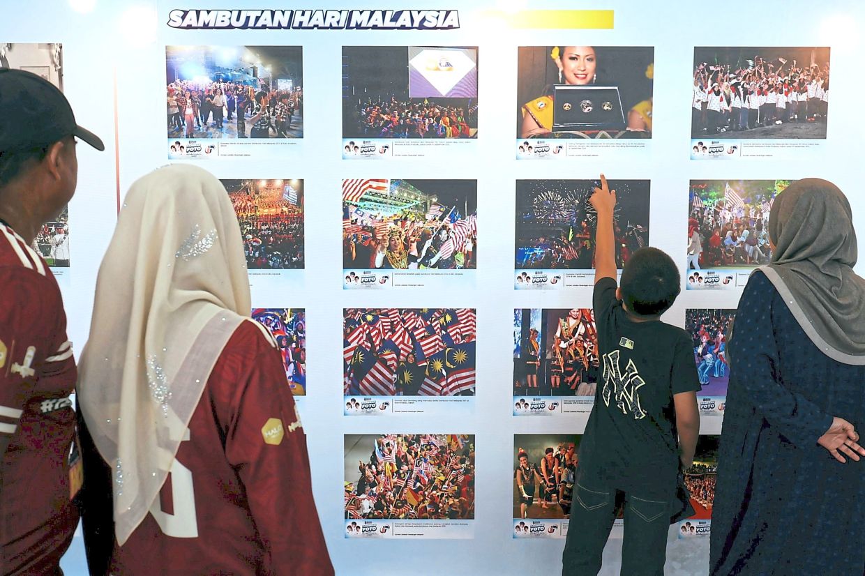 Visual history: Visitors checking out a picture exhibition during the Malaysia Day celebration at the PICCA Convention Centre @ Butterworth Arena in Penang. — CHAN BOON KAI/The Star 