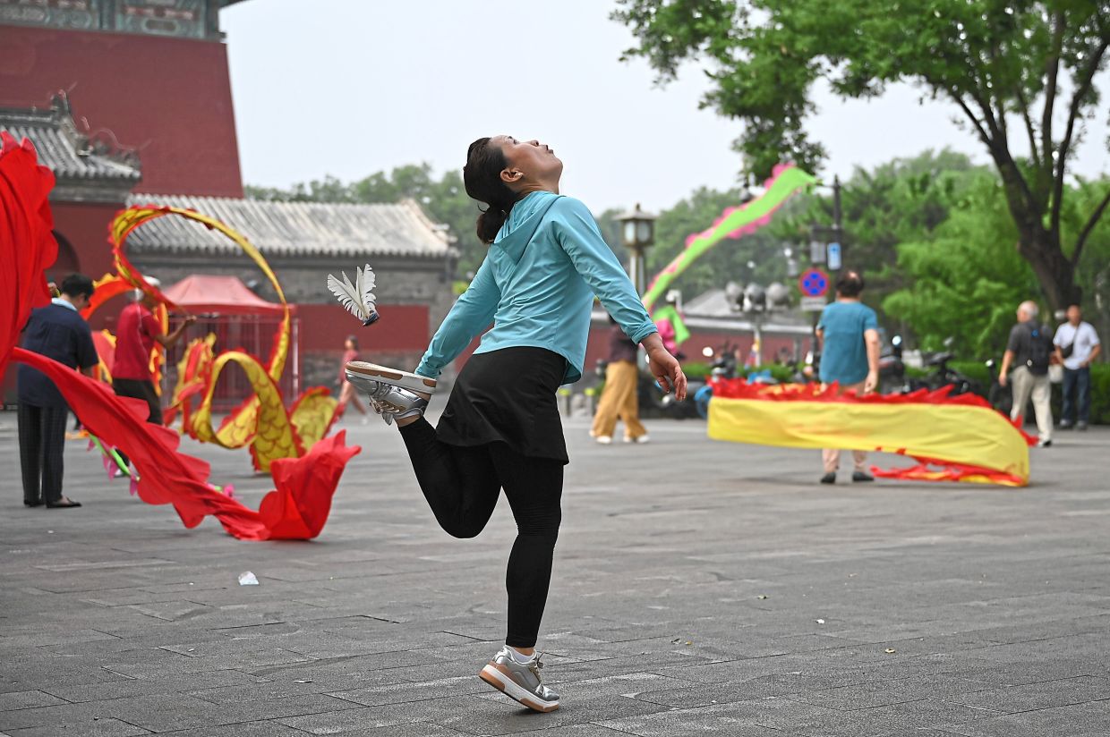 A Chinese woman seen playing Jianzi, where a feathered shuttlecock is kept in the air, sometimes with acrobatic skill. — JOHANNES NERDECKER/dpa