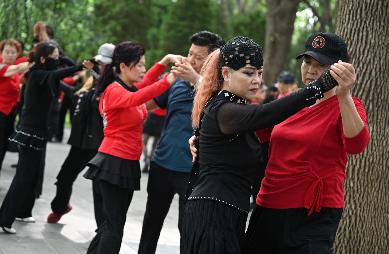 Ge Fang (second from the right) dances with another woman in a Beijing park. Photo: Johannes Neudecker/dpa