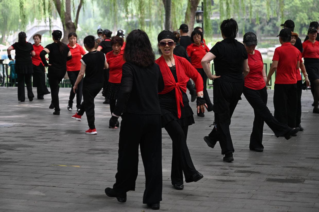 Men and women dance in a square in a Beijing park. Photo: Johannes Neudecker/dpa