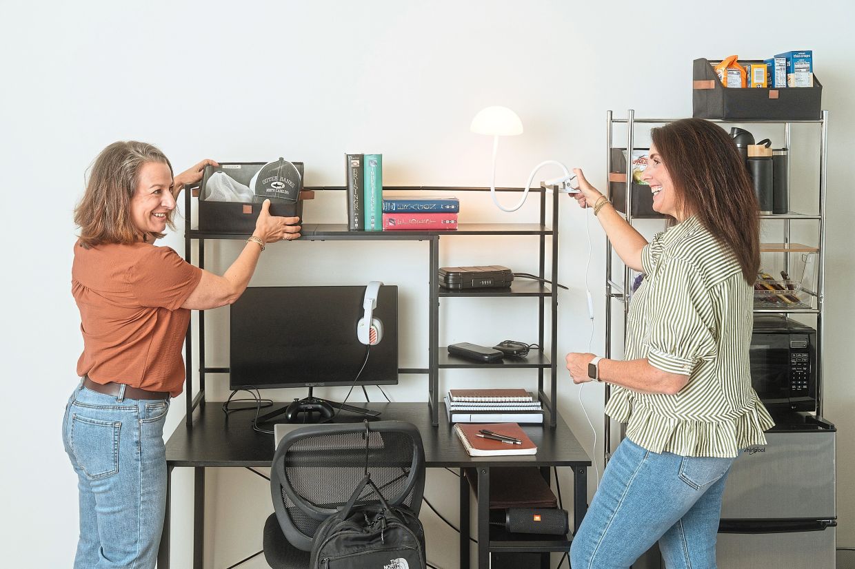Zirkle (left) and Christiano, who have been a part of a total of 18 dorm move-ins, adjust a practice dorm setup in Christiano’s home. — WILL CROOKS/The New York Times