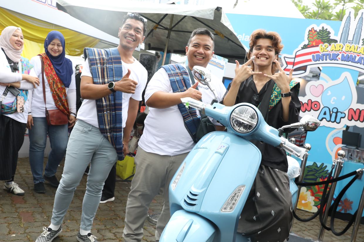 Adam (centre) with lucky draw prize winner Muhammad Akmal (far right) and his new Vespa.