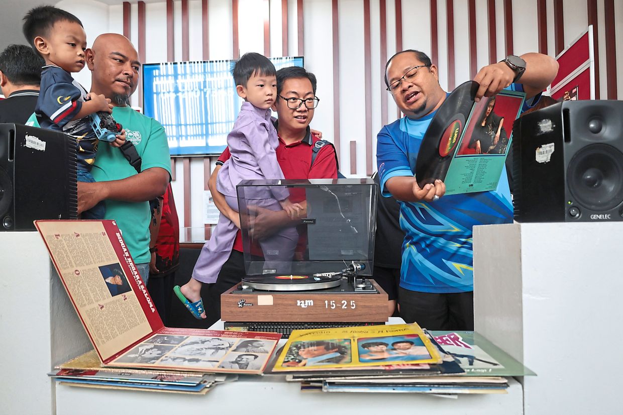 Chew (centre) and his son Khai Jie, dressed in ‘baju melayu’, checking out the gramophones, vinyl records and other vintage broadcast and music equipment at the Mutiara FM radio station.