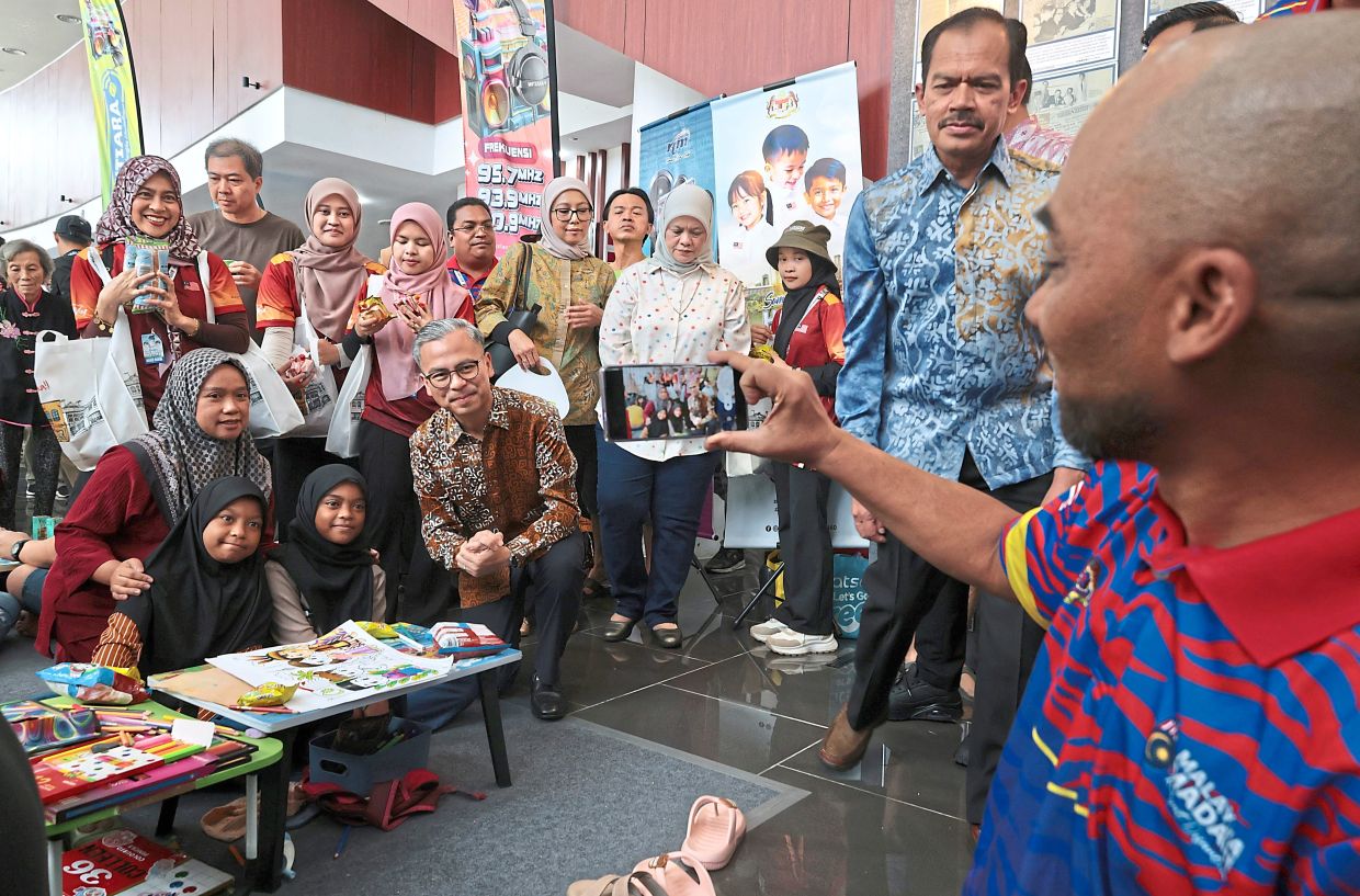 Fahmi (kneeling, centre) posing for a photo with visitors while making his rounds during the event.