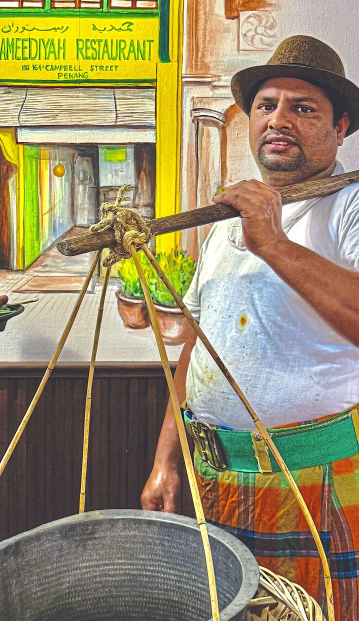 (Below) A Hameediyah employee demonstrating how rice and curries used to be carried on poles, thus creating the name ‘nasi kandar’.