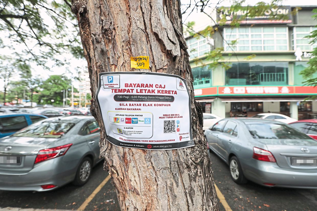 A sticker posted on a tree in Kuchai Entrepreneurs Park’s commercial area informing motorists of DBKL’s charges and apps to use when paying for parking.