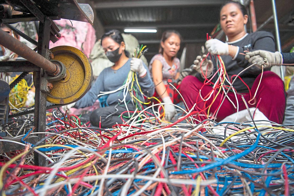 Workers removing copper from industrial wiring inside a recycling shop. — AFP
