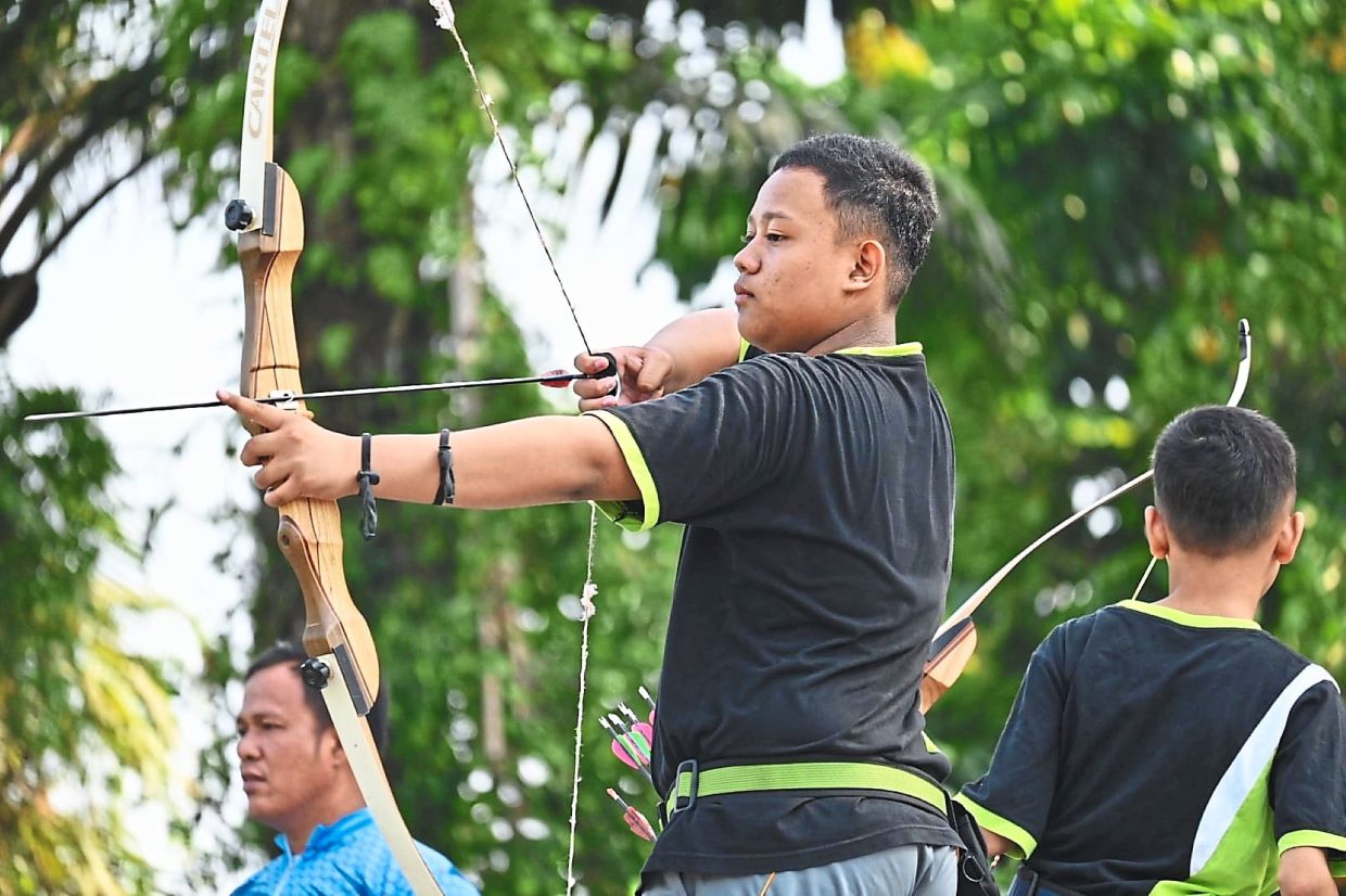 A junior archer drawing his bow with a finger tab.
