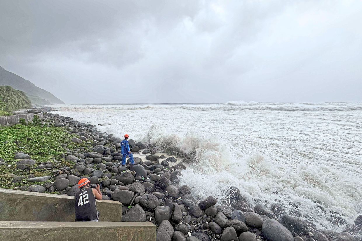 People watching as strong waves batter Basco, Batanes province in northern Philippines. — AFP/AP