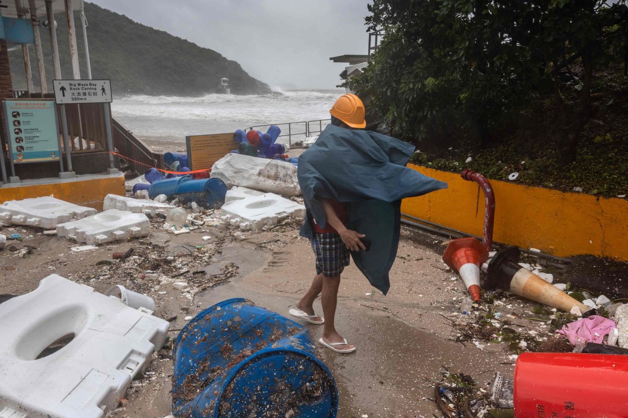 A man walking past debris left on a beach as Ragasa moved past Hong Kong on Sept 24.- AFP