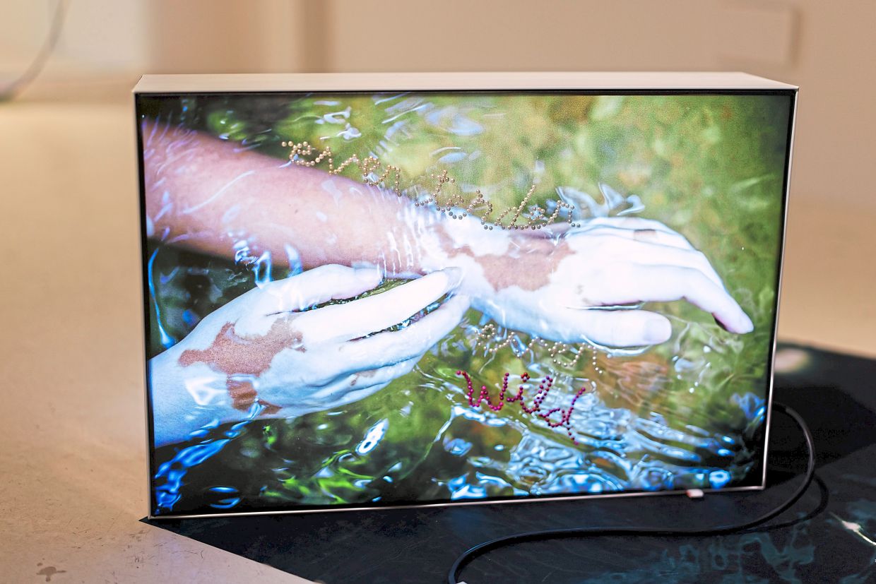 A work titled 'ever shifting, ever fluid' (2025) by Nadirah, featuring pearl-pinned text on a double-sided lightbox and printed fabric. Photo: All Is Amazing