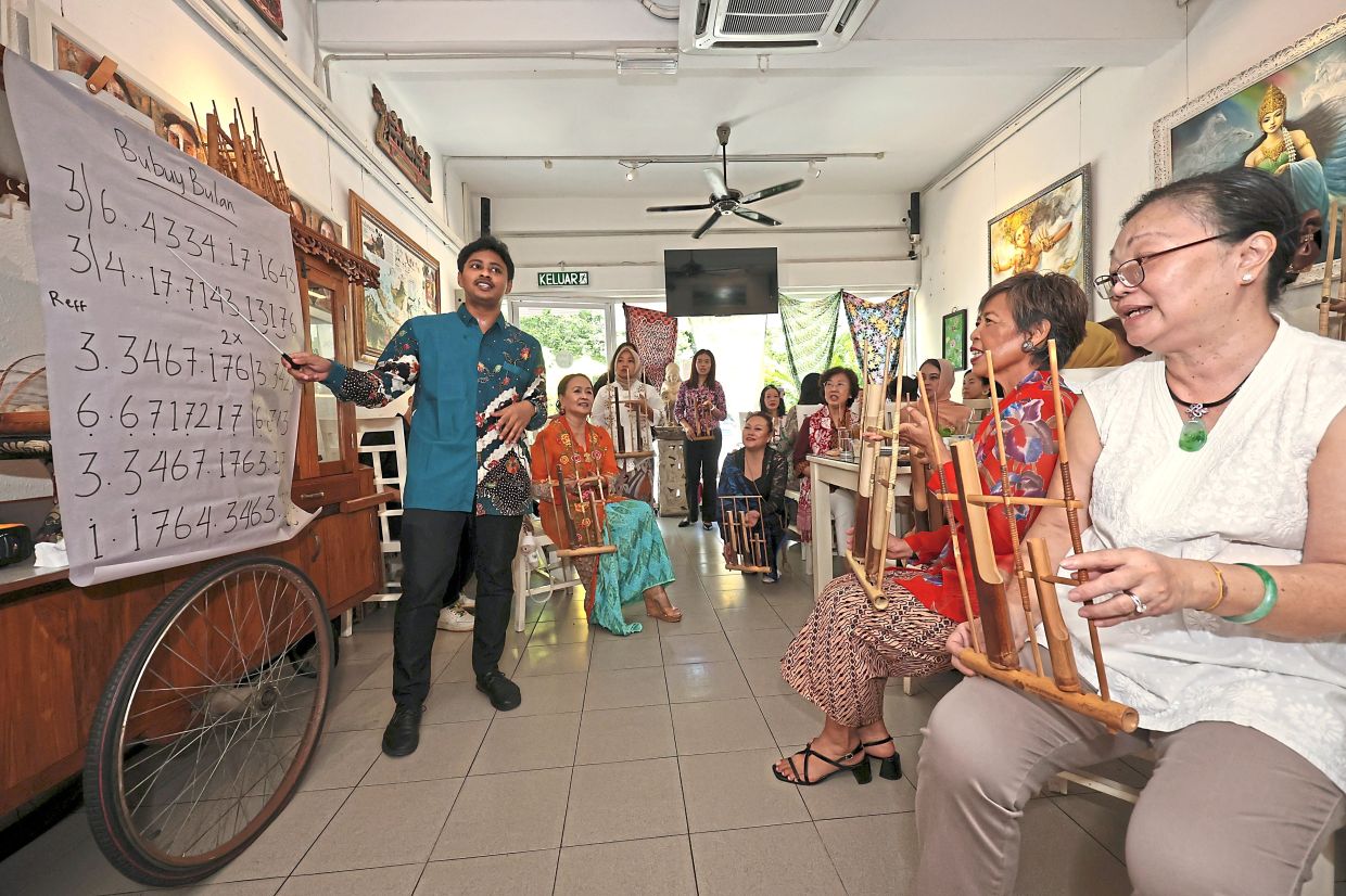 Difa (left) teaching AIP members how to play the angklung.
