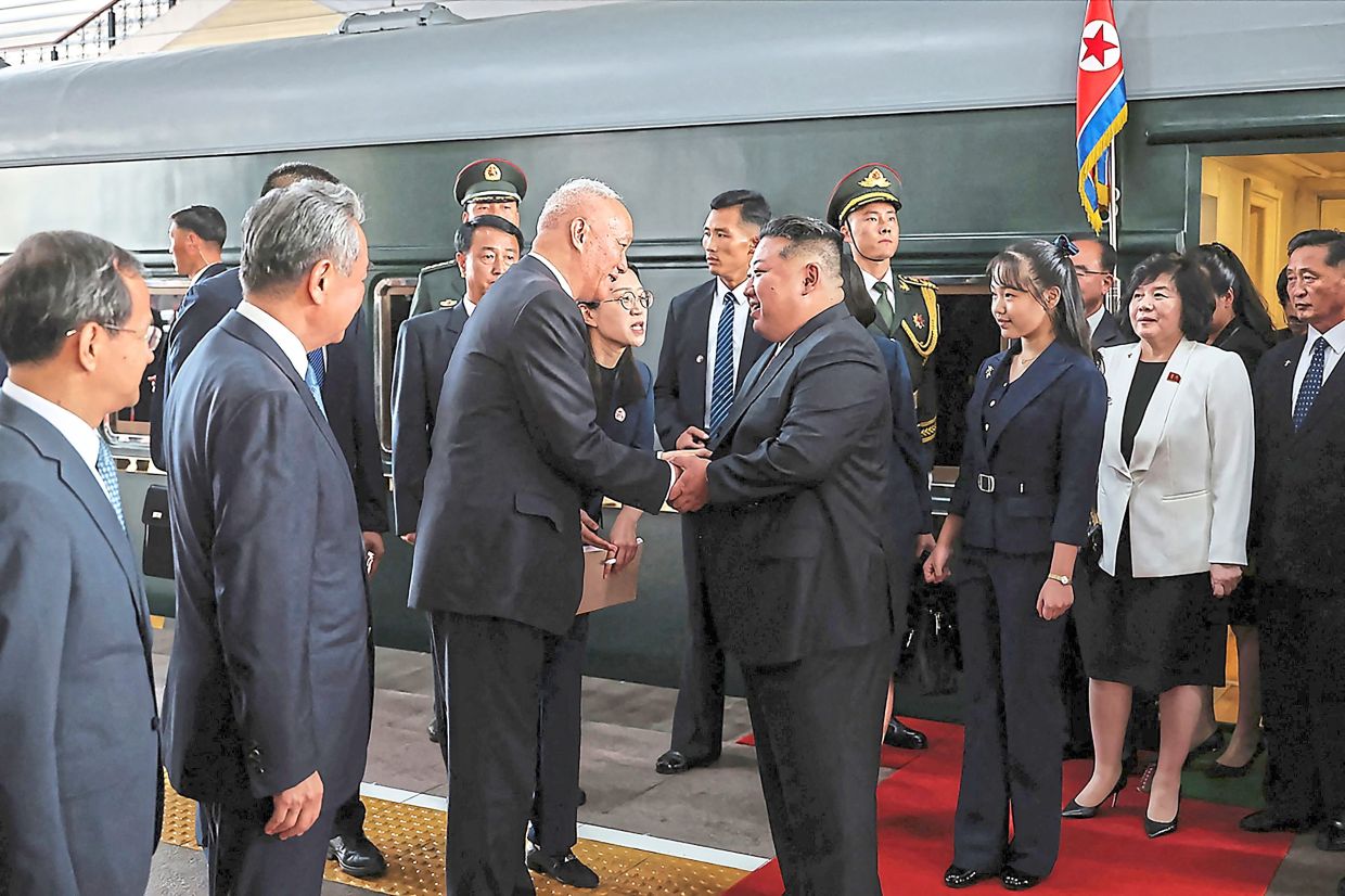 Jong-un and Ju-ae being greeted by China’s Secretary of the Central Secretariat of the Communist Party Cai Qi (left) upon their arrival at the Beijing Railway Station in Beijing. — AFP