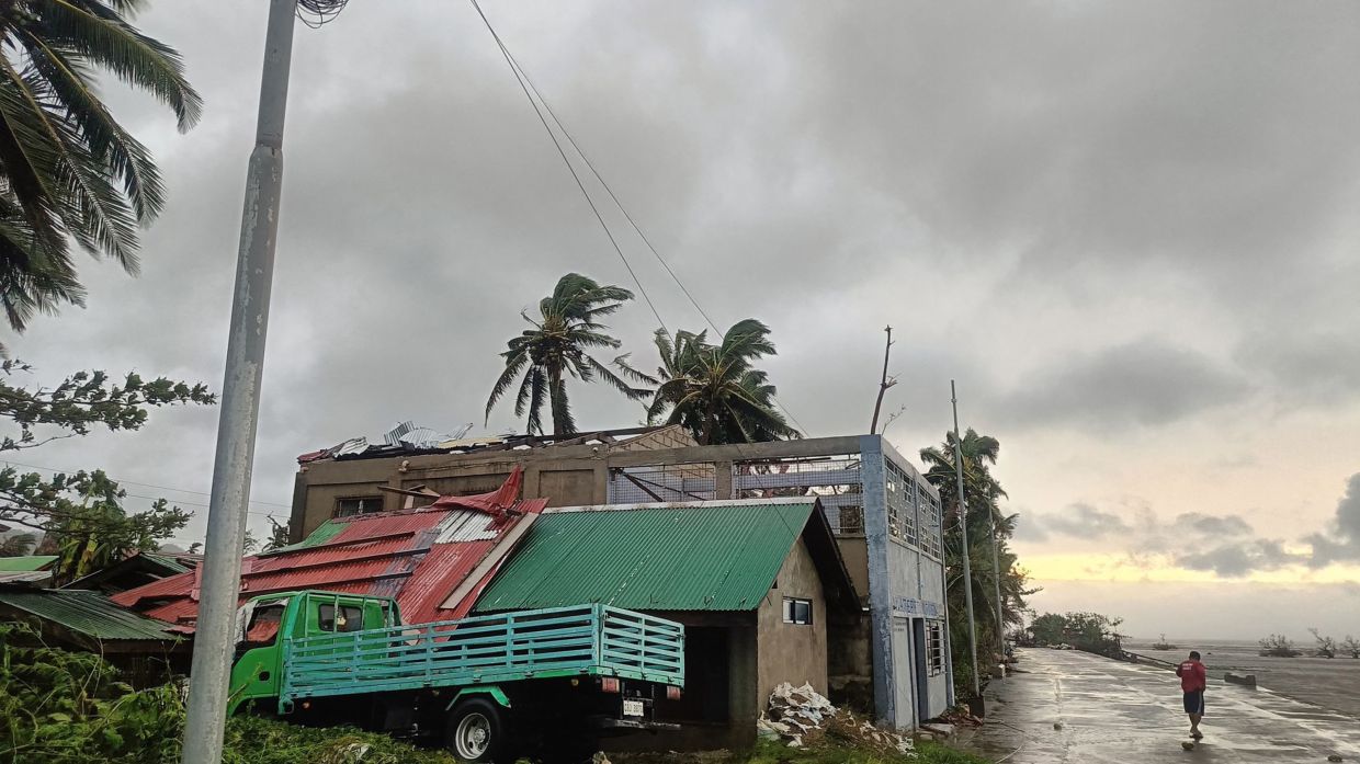 A resident walking past a building with ripped roof destroyed at the height of storm Bualoi, in Masbate City, Bicol region, south of Manila. - Courtesy of Facebook page of Jerome Martinez via AFP