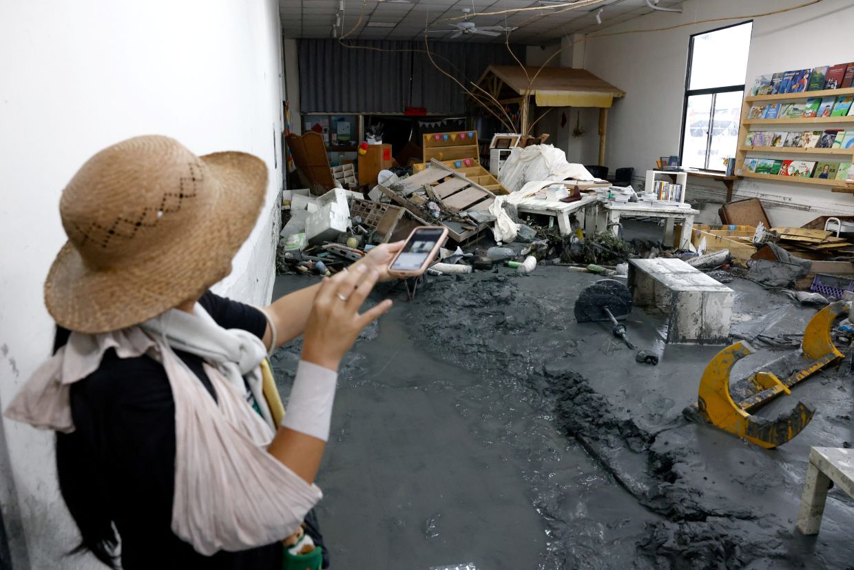A bookstore staff pointing at the damage inside her shop in the aftermath of flooding brought by Ragasa in Hualien on Sept 26. - Reuters