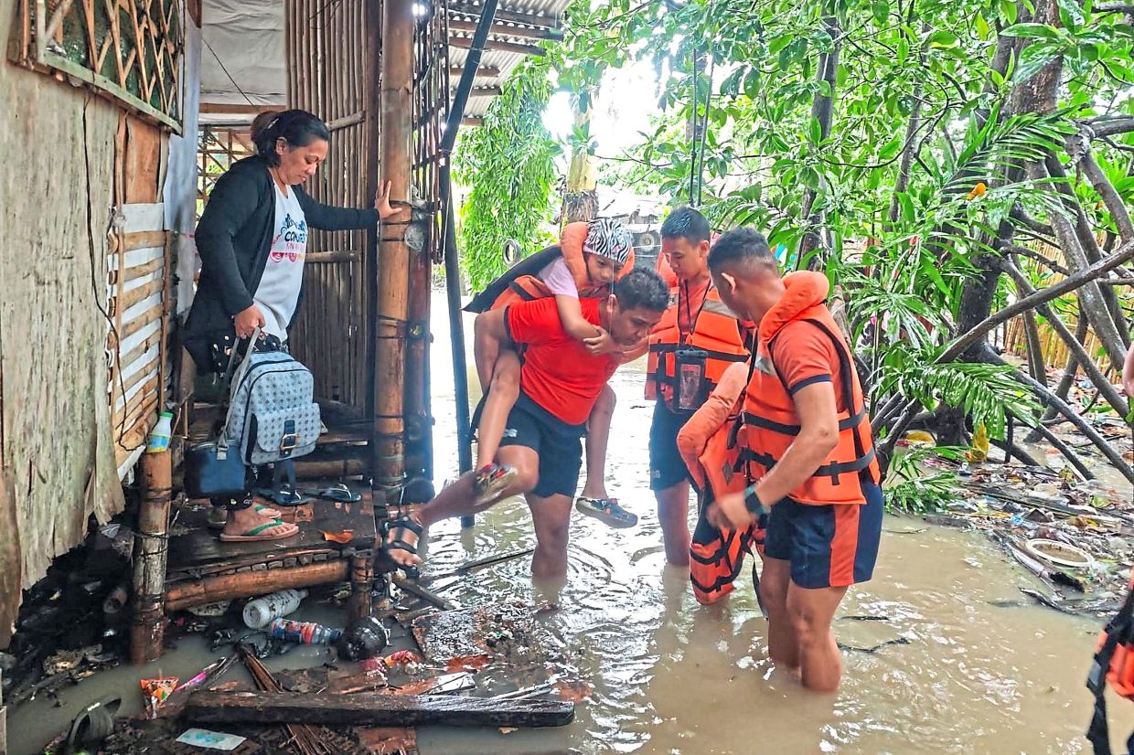 Philippine Coast Guard rescuers move residents to safer ground as floods rise.— AFP/AP