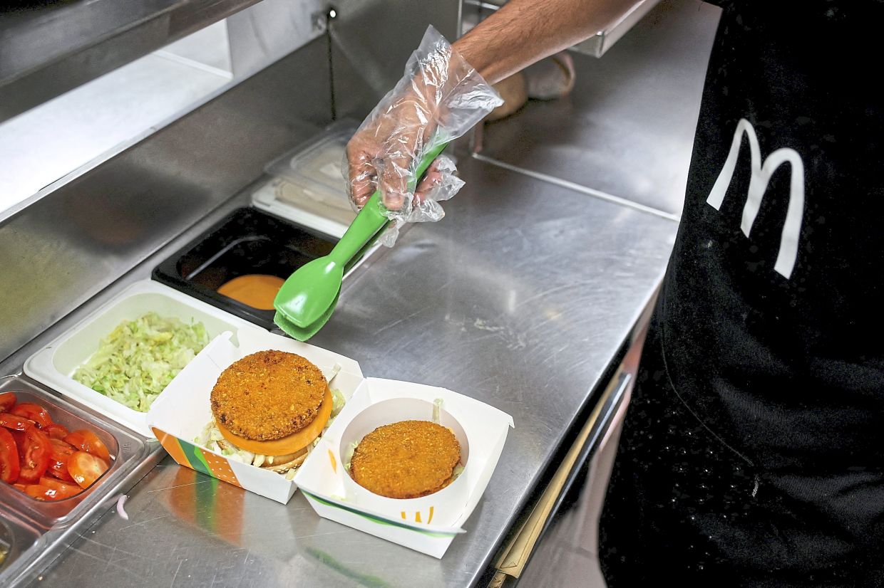 An employee preparing a Maharaja Mac vegetarian burger with an added protein slice at a McDonald’s branch in Mumbai, India. — Reuters