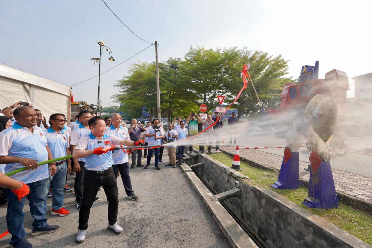 Local government and tourism committee chairman Datuk Ng Suee Lim hoses down dirt as part pf a gimmick launch of the World Clean-up Day at Dataran Klang@Padang Chetty in Klang while Klang mayor Datuk Abd Hamid Hussain (on Ng’s left look on) with others witnessing the event.