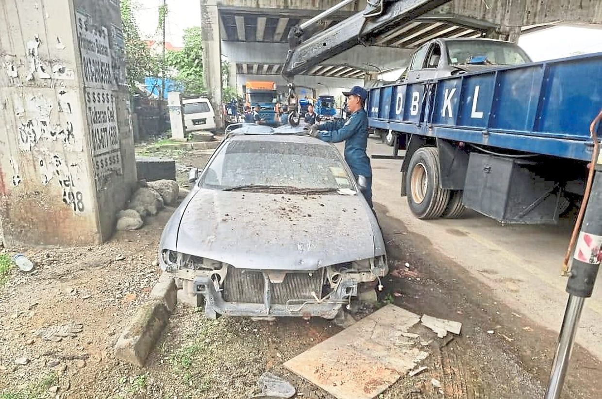 An old car left abandoned under a bridge being towed to the depot by DBKL contractors. — Filepic