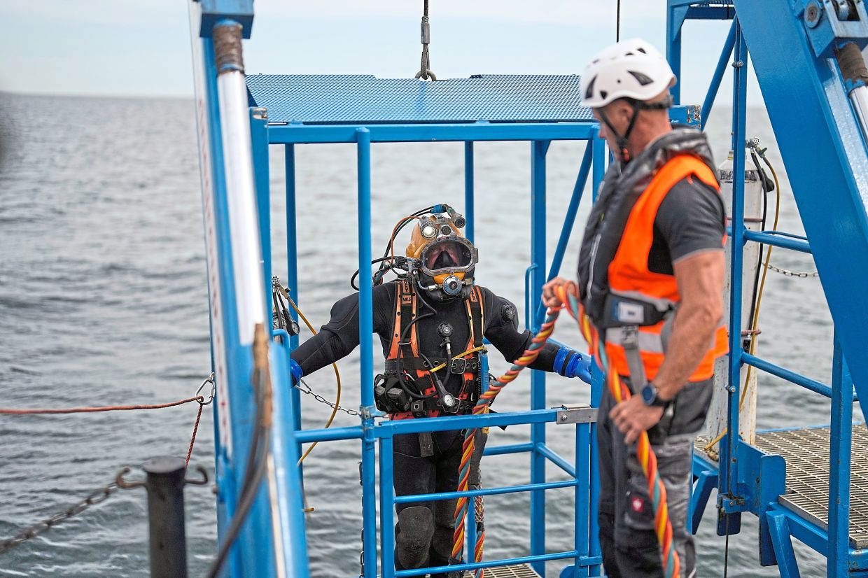 A diver is lowered into the water to retrieve ammunition from the sea floor.