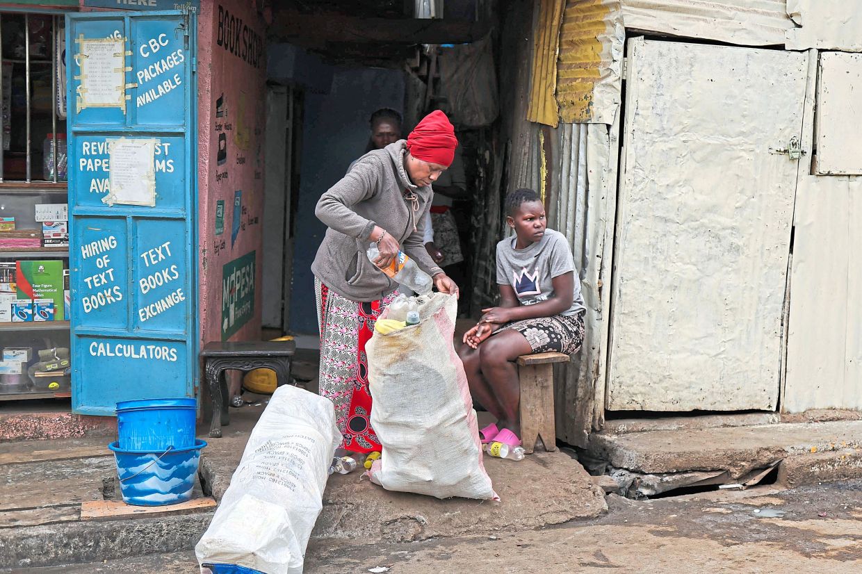 John collects discarded plastic waste along a street in her neighborhood.