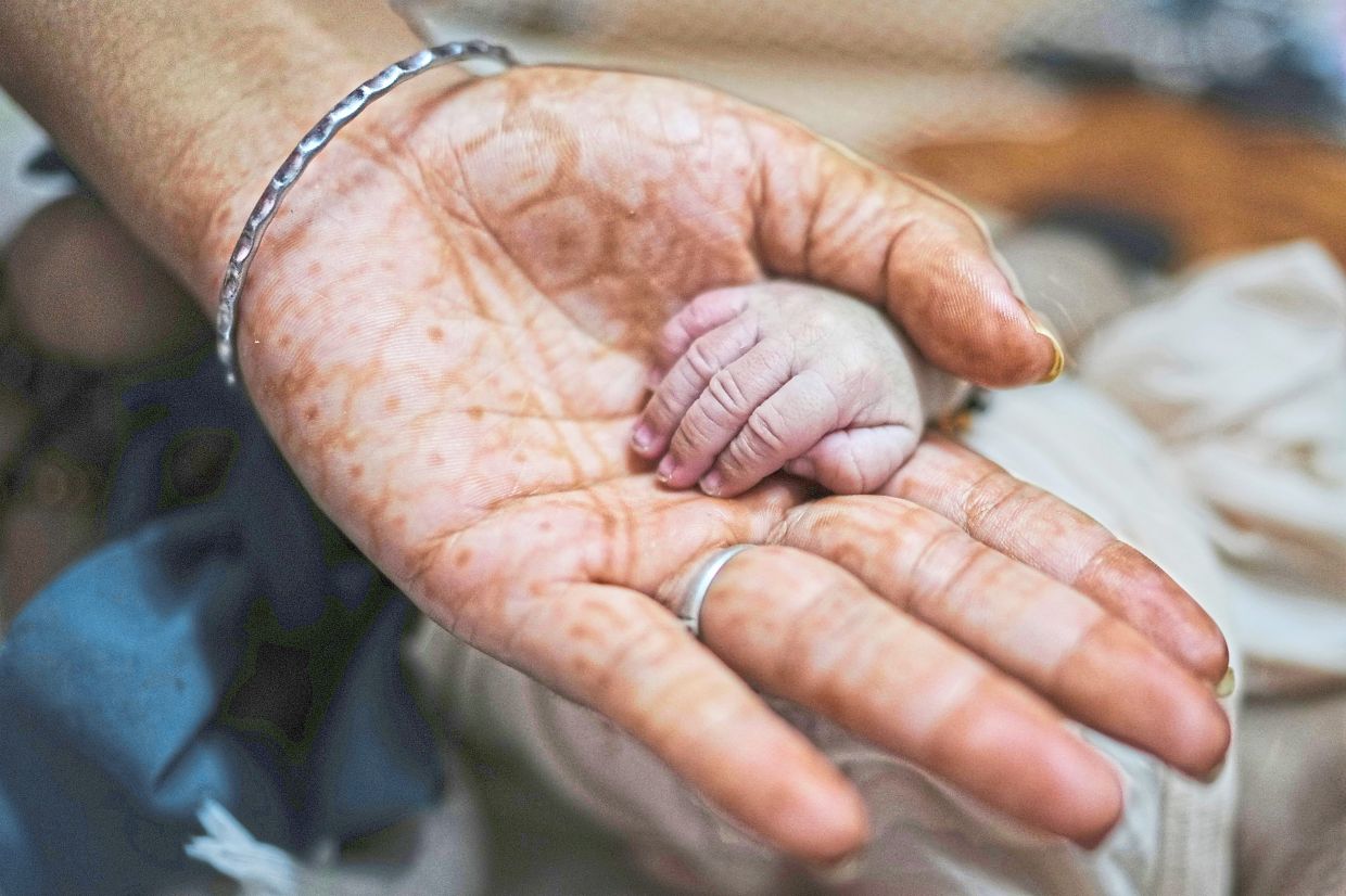 Antima holds the hand of her newborn nephew at their house. Photo: AP