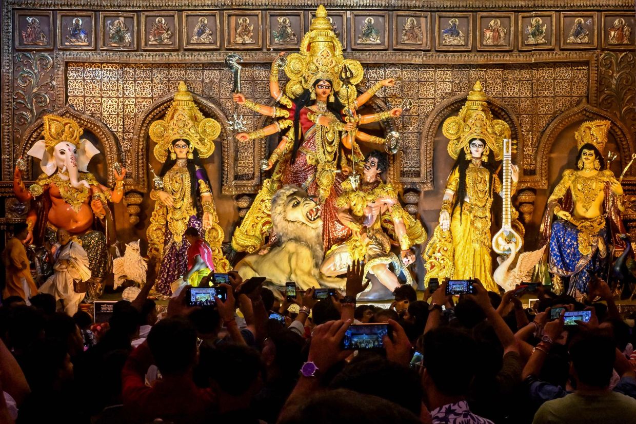 TOPSHOT - Devotees take photographs as they visit a 'Pandal' (temporary structure for worship) with an idol of the Hindu goddess Durga on the eve of the Durga Puja festival in Kolkata. -- Photo by Dibyangshu SARKAR / AFP