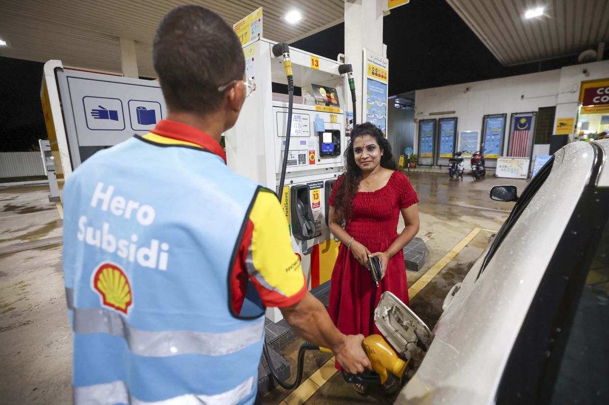 Petrol station employee Mohd Firdaus Ambak helping consumer Saraswathy Ramasamy, 42,at a petrol station in Semambu, Pahang. - Photo: Bernama