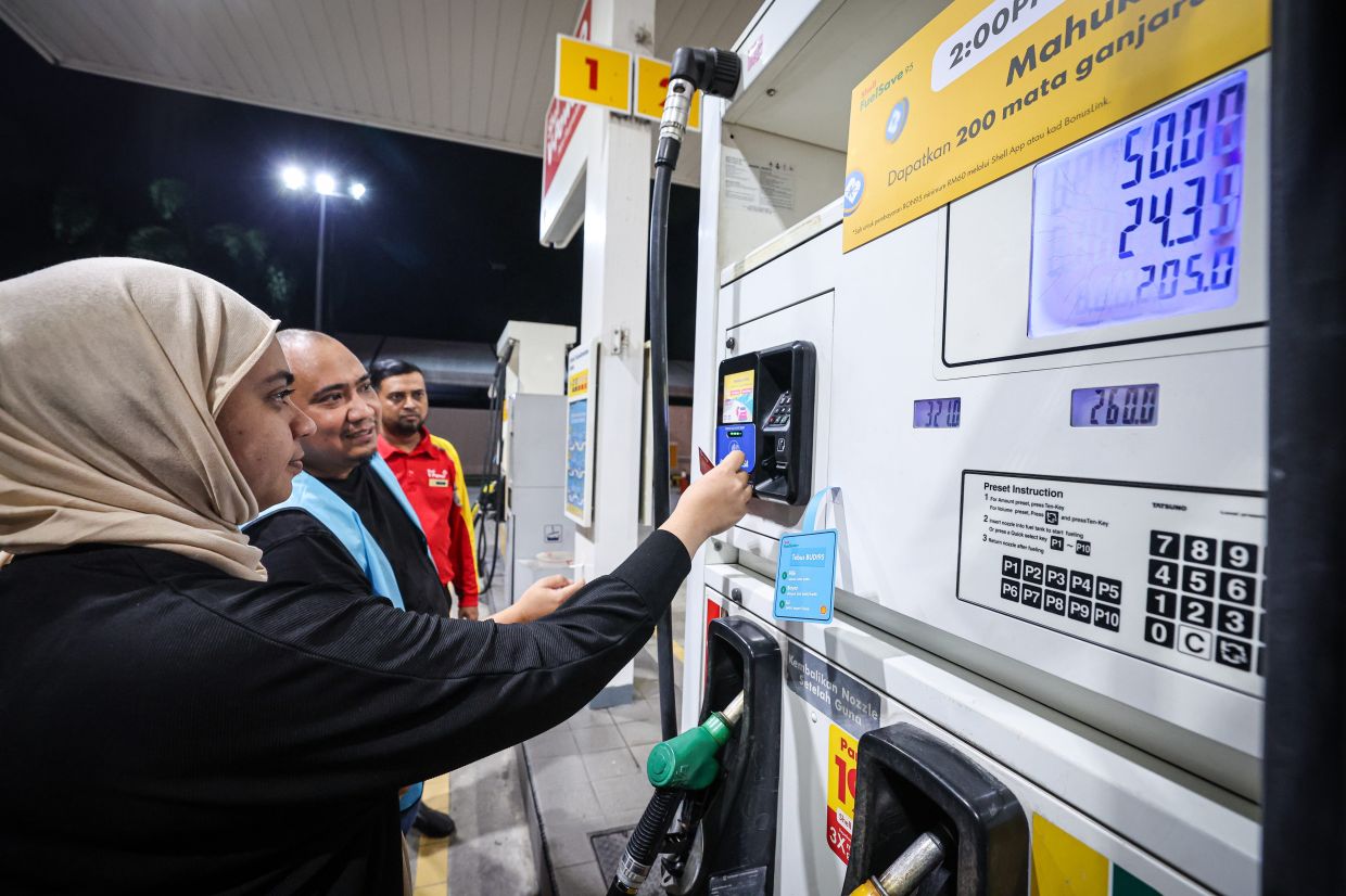 Petrol station owner Wan Muhammad Hafidz helping a consumer with the process of using the Budi95 subsidy in Kuala Lumpur. - Photo: Bernama