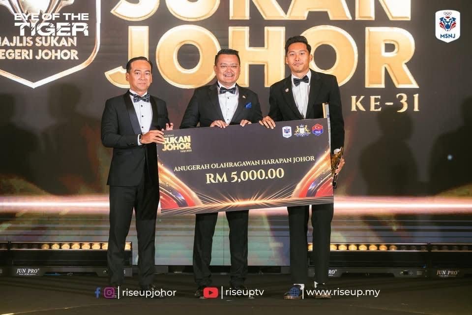 State youth, sports, entrepreneur development and cooperatives committee chairman Mohd Hairi Mad Shah (centre) presenting the Johor Promising Sportsman award to sprinter Umar Osman (right) while Johor Sports Council (MSNJ) director Mohd Ekmaluddin Ishak looks on. (Photo from MSNJ Facebook)