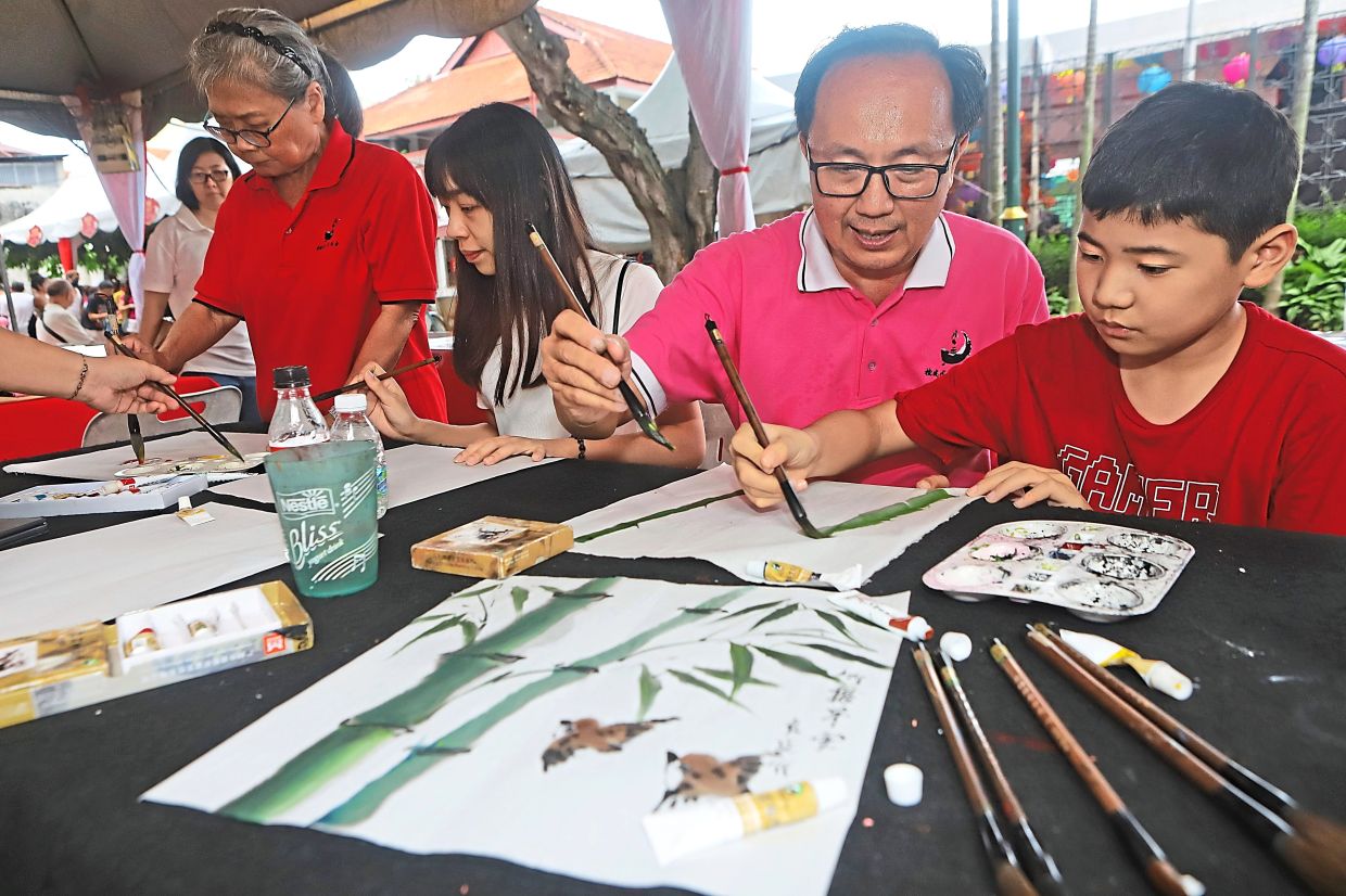 Loh (second right) teaching a child Chinese brush painting at the Mid-Autumn Carnival.
