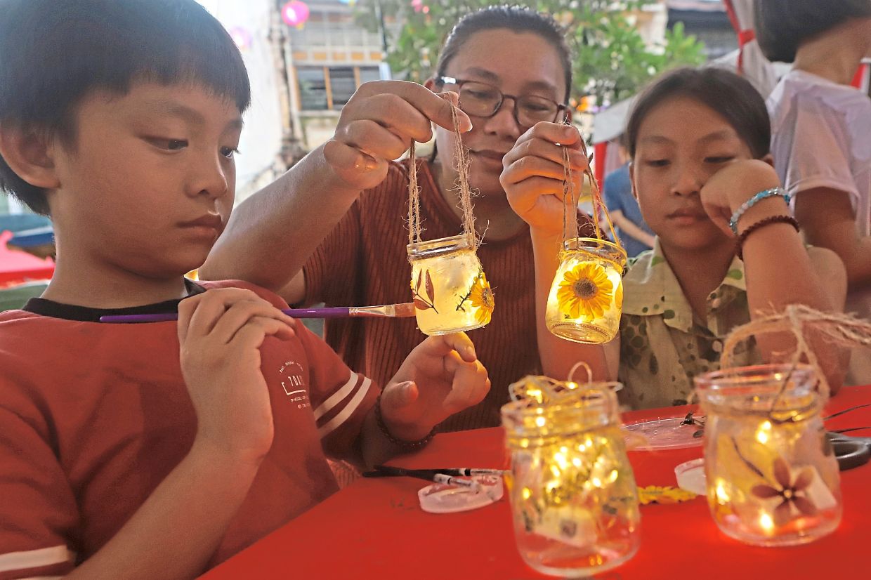 Yong and her children Jiun Sen (left) and Jiun Nee making lanterns out of glass jars at a workshop.