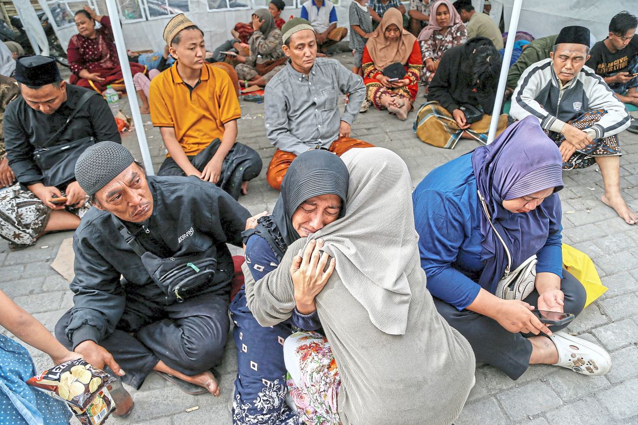 Holding on to hope: A victim’s family member crying in the company of relatives near the school collapse. — Reuters 