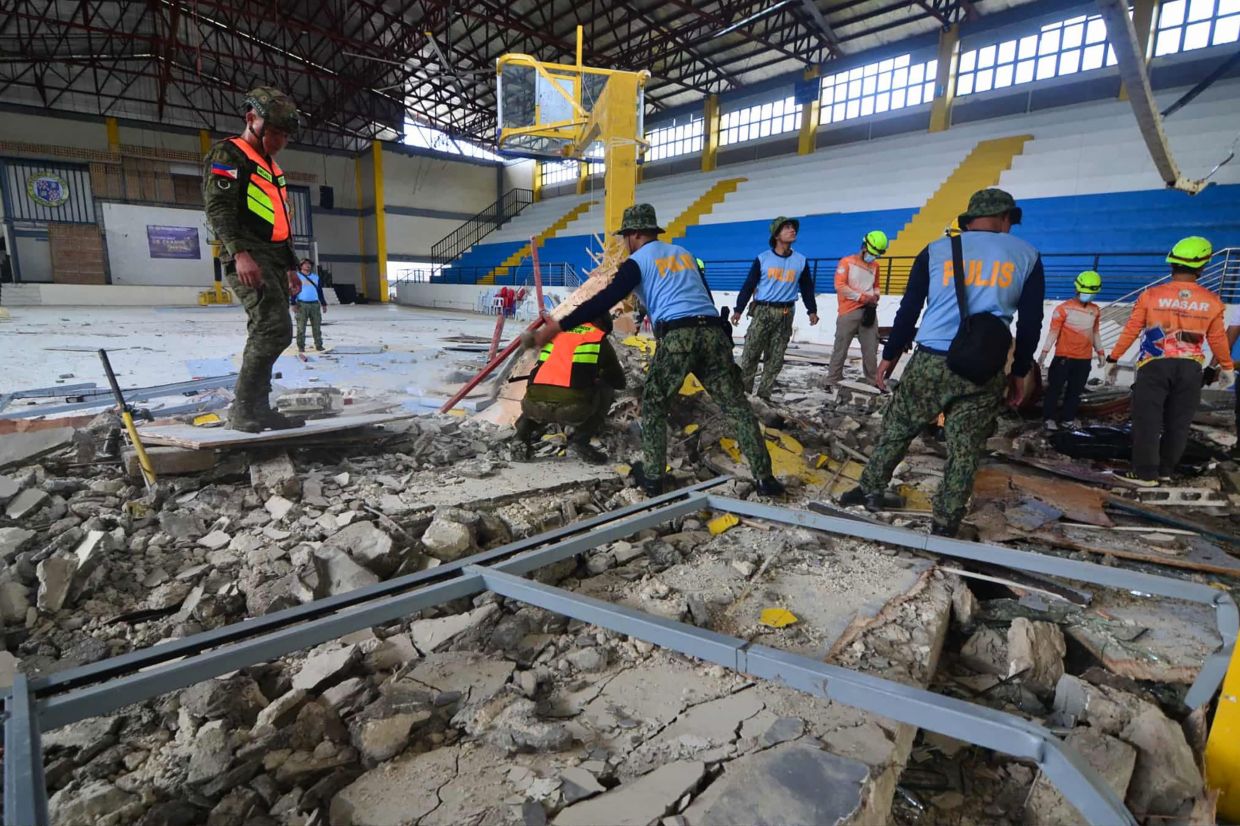 The police and rescuers inspecting the damage at an indoor arena in San Remigio town, Cebu province on Oct 1. - AFP