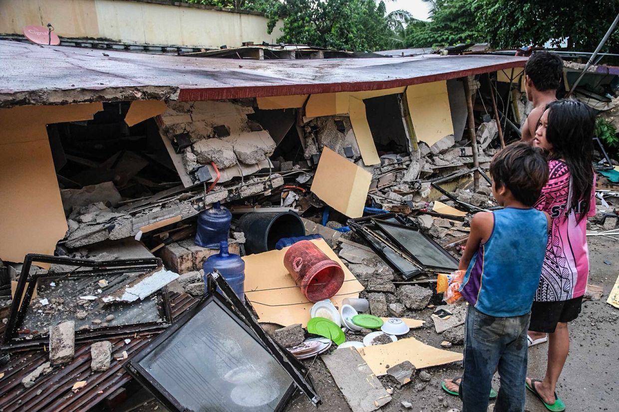 People looking at a collapsed building in Bogo City, Cebu province on Oct. 1, 2025 after the earthquake on Sept 30. -AP 