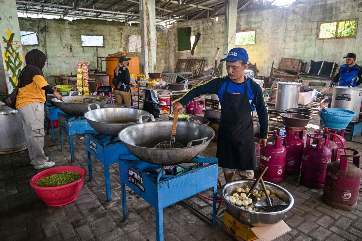 Volunteers prepare food for families of victims gathered at the Al Khoziny Islamic boarding school in Sidoarjo, East Java province on October 1, 2025, after a multi-storey building at the school collapsed. Around 91 people are believed to be still trapped under the ruins of a collapsed school on Indonesia's main island of Java, National Disaster and Mitigation Agency spokesperson Abdul Muhari said. - Photo: AFP