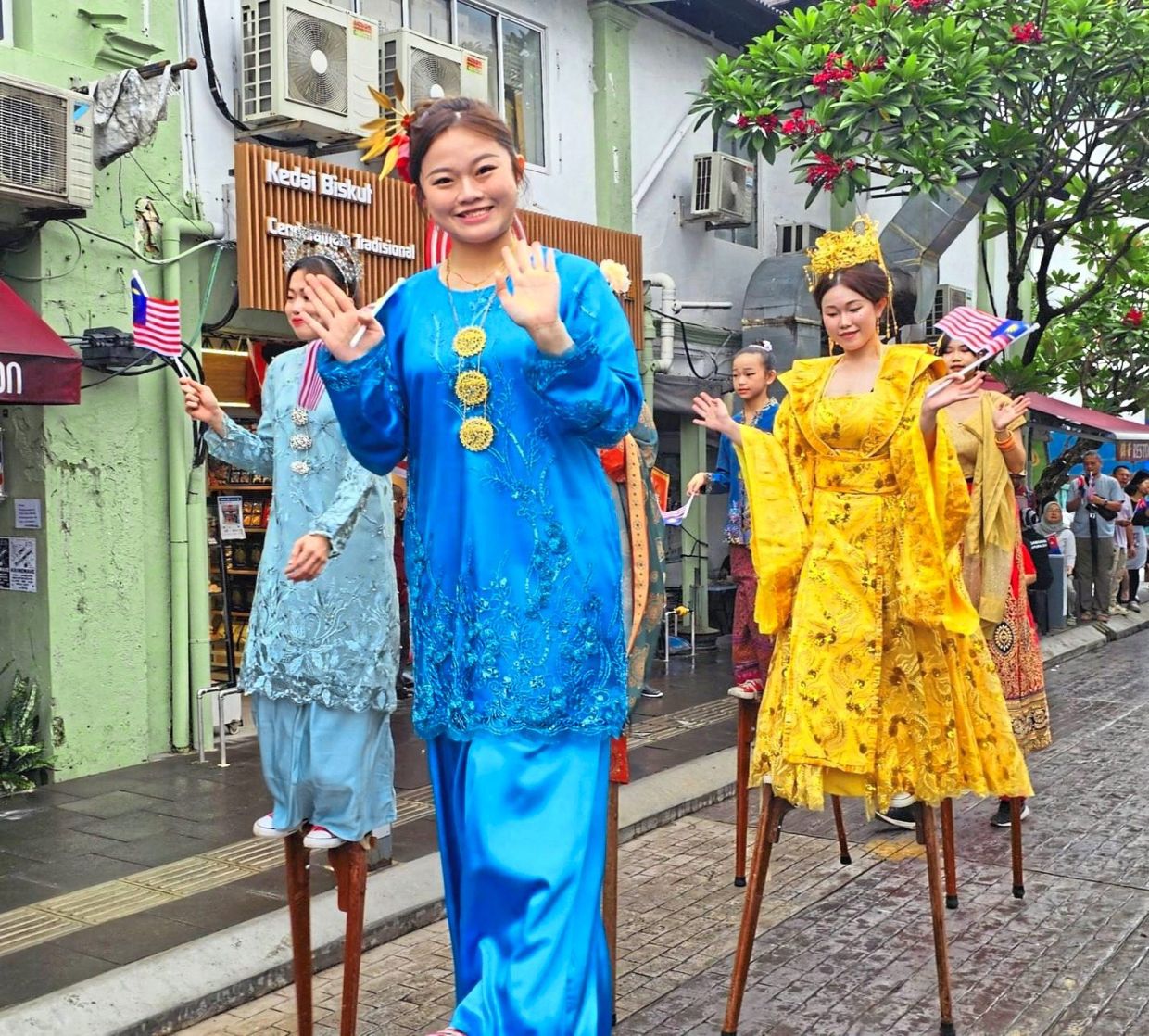Stilt walkers waving to visitors during a National Day celebration at Jalan Tan Hiok Nee.