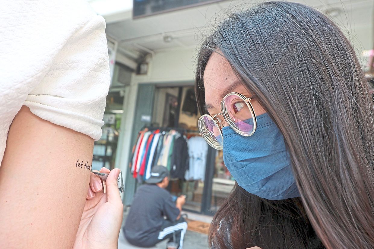 Tan creating a design on a customer’s arm at her stall.