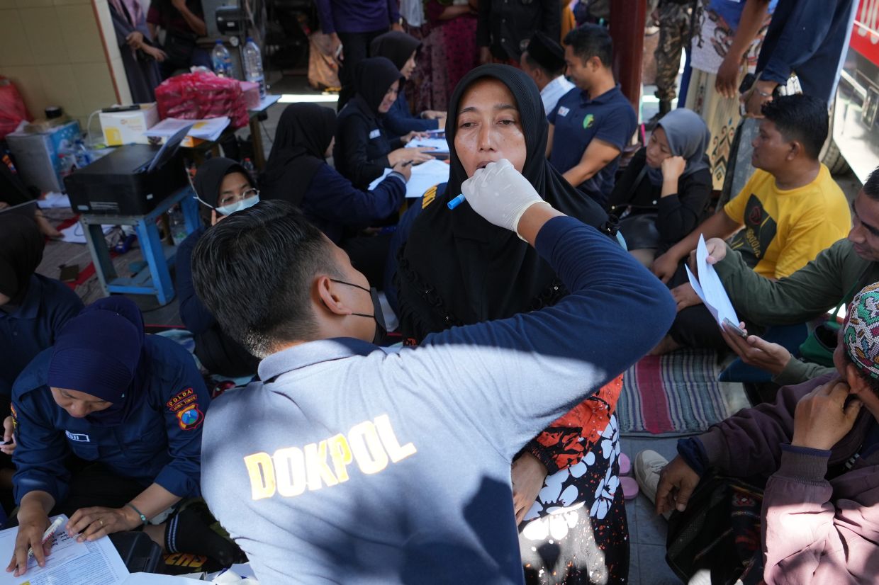 Members of police forensic unit collect DNA sample from students' family members after a building under construction collapsed Monday at an Islamic boarding school in Sidoarjo, East Java, Indonesia, Thursday, Oct 2, 2025. - Photo: AP