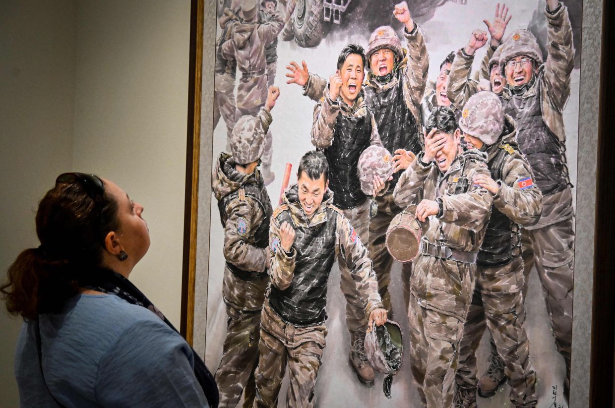 A visitor inspects the painting 'Big Victory Joy' by Choe Dong Il at the exhibition in Moscow. Photo: AFP