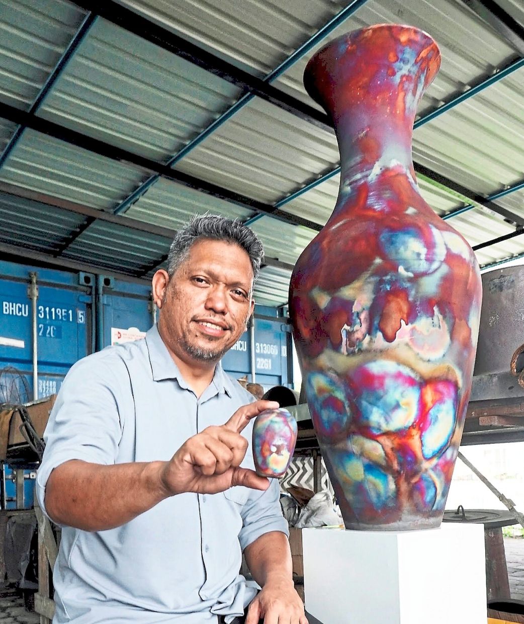 Adil showing vases made using the raku firing technique.