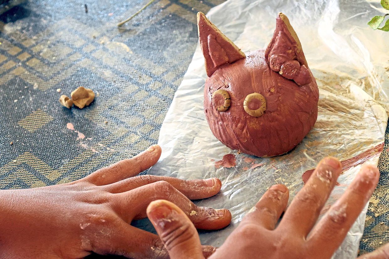 A participant making a ceramic cat during the workshop at Persera.
