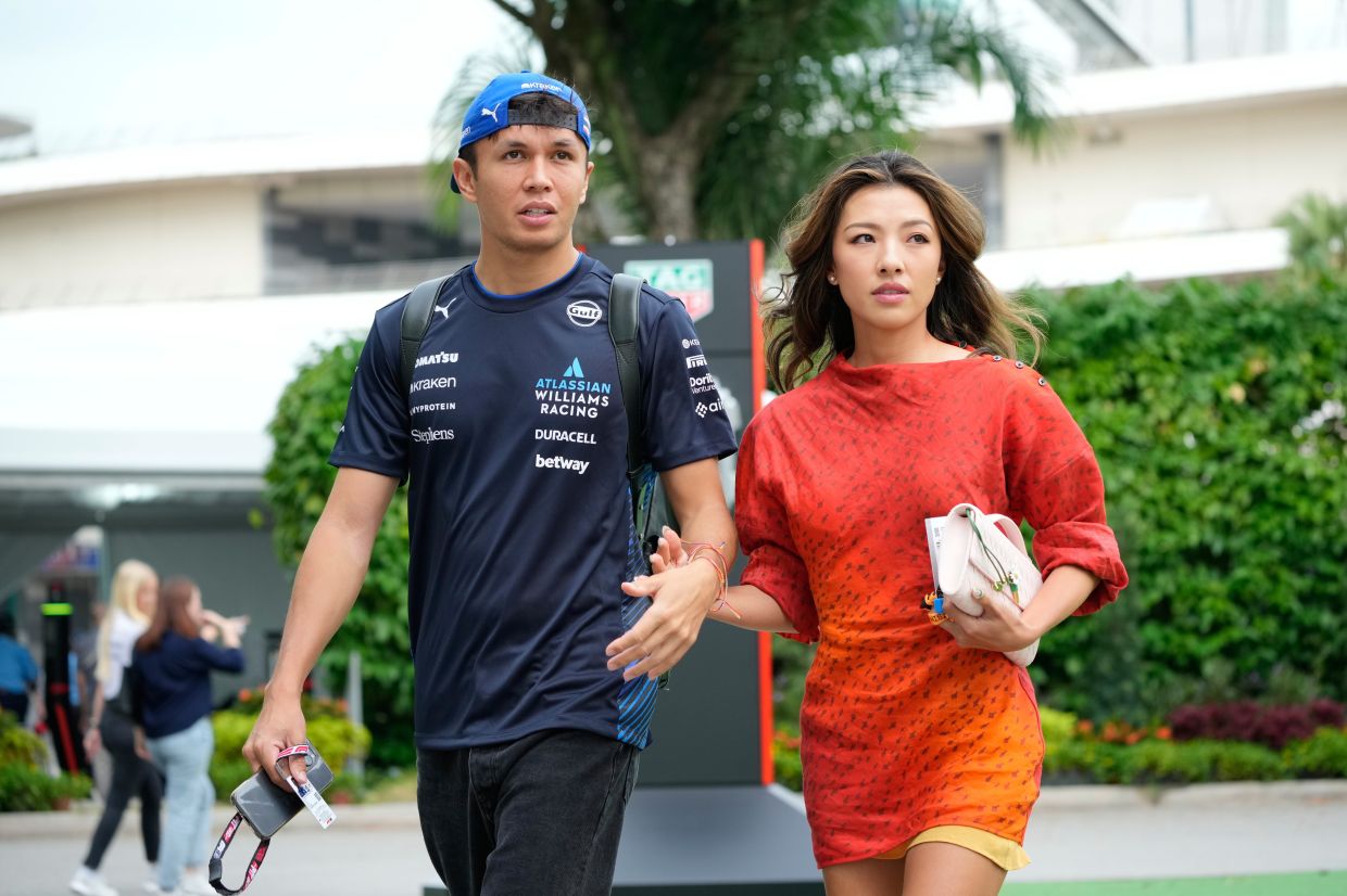 Williams driver Alexander Albon of Thailand (left) walks with his girlfriend Lily Muni He as they arrive ahead of the first practice session of the Singapore Formula One Grand Prix at the Marina Bay Street Circuit in Singapore, on Friday, Oct. 3, 2025. -- AP Photo/Vincent Thian